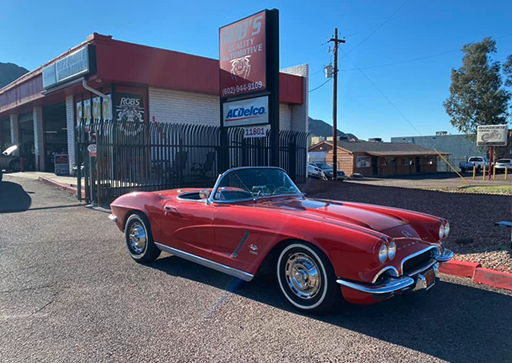 Red 1962 Chevrolet Corvette convertible in front of the shop